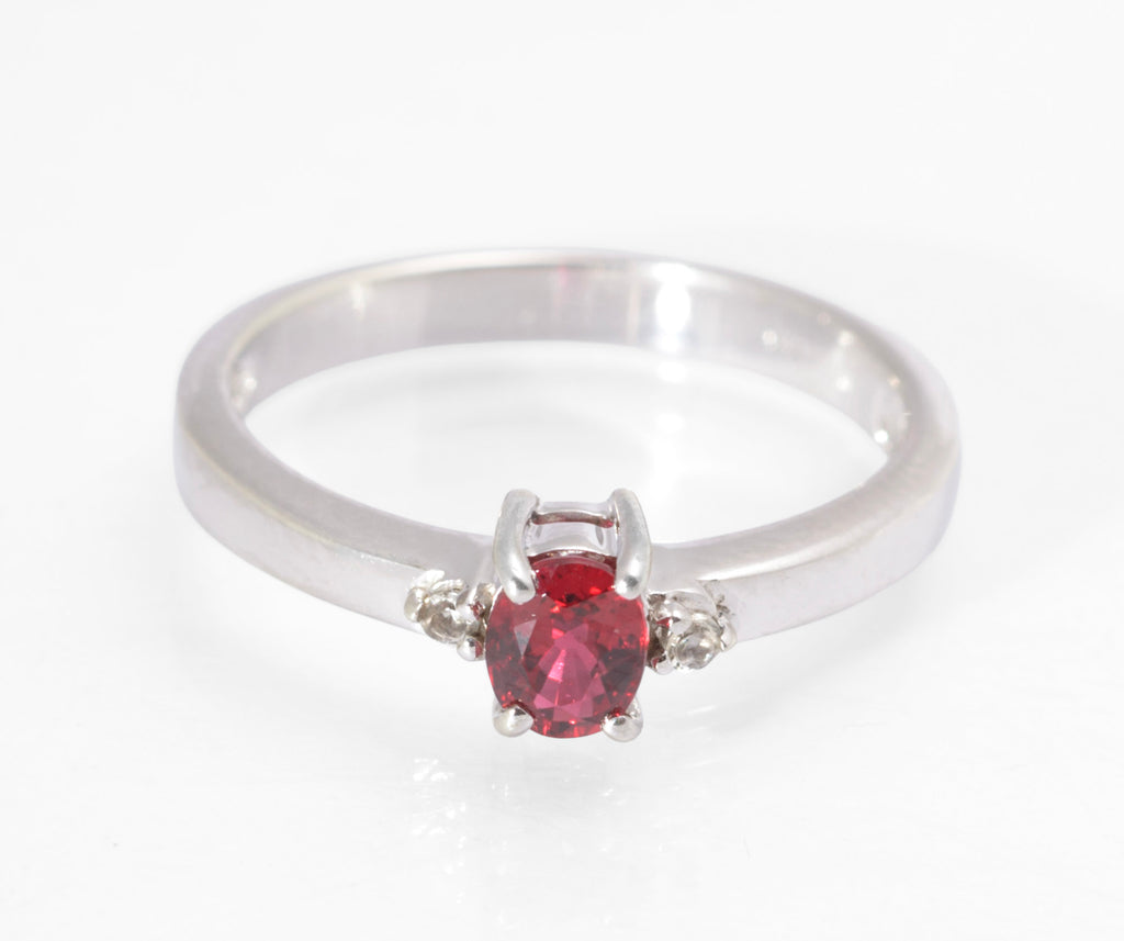 A vintage 9ct white gold ring set with an oval brilliant cut lab created ruby flanked by two white topaz accent stones, in a generously proportioned band hallmarked Birmingham 2007.