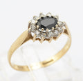 A vintage 9ct gold ring set with a natural midnight blue sapphire in an east-west orientation, surrounded by a CZ halo in a low cathedral mount with bifurcated shoulders, Birmingham hallmarked 1986.