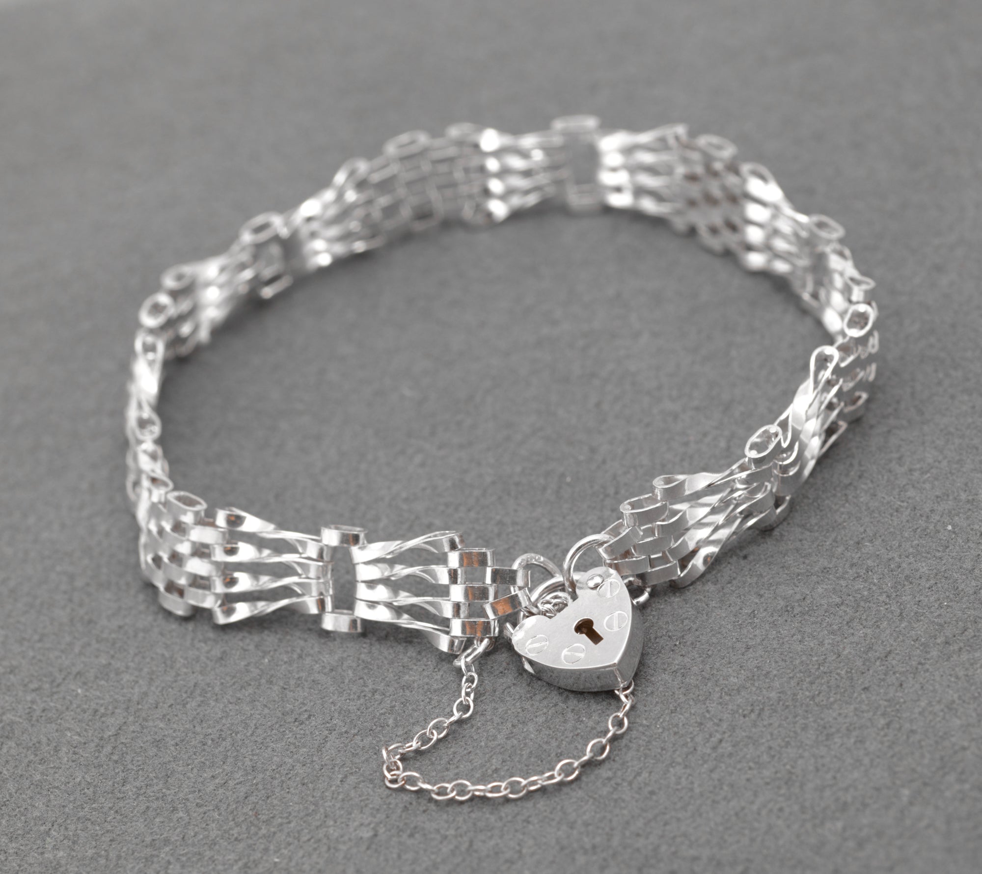 Vintage Sterling Silver Gate Bracelet - overhead view showing open gate link design and heart padlock on grey