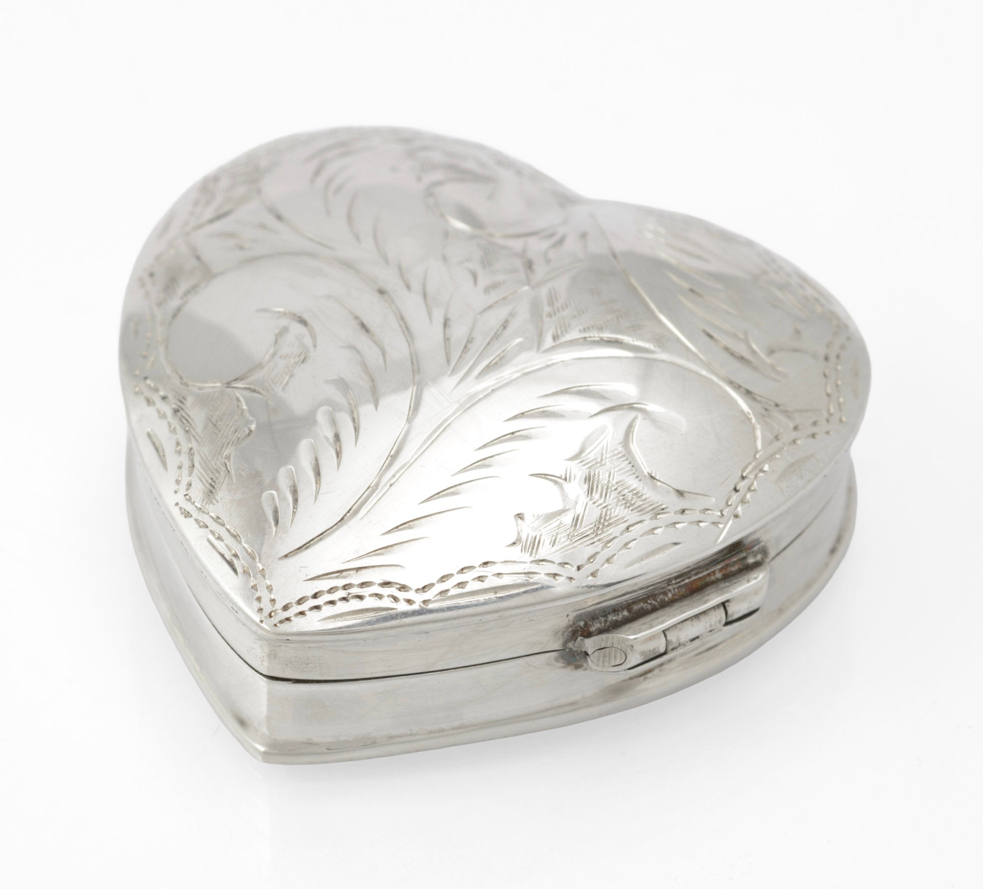 Vintage sterling silver heart shaped trinket box - three-quarter view showing engraved scrolling foliate lid with dotted border and hinge detail
