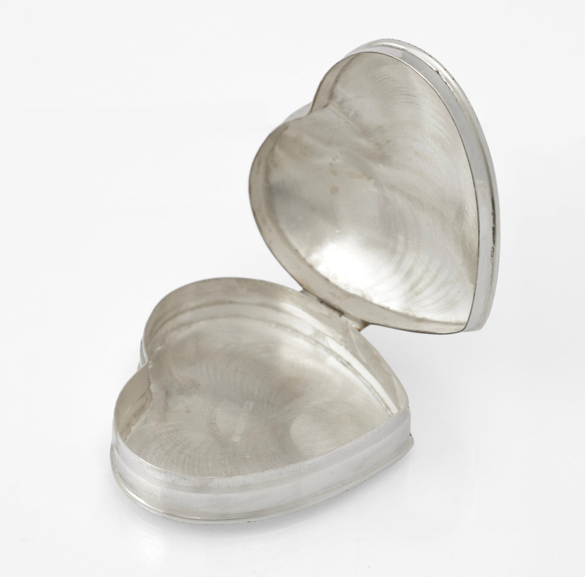 Vintage sterling silver heart shaped trinket box - angled view showing engraved foliate decoration across domed lid