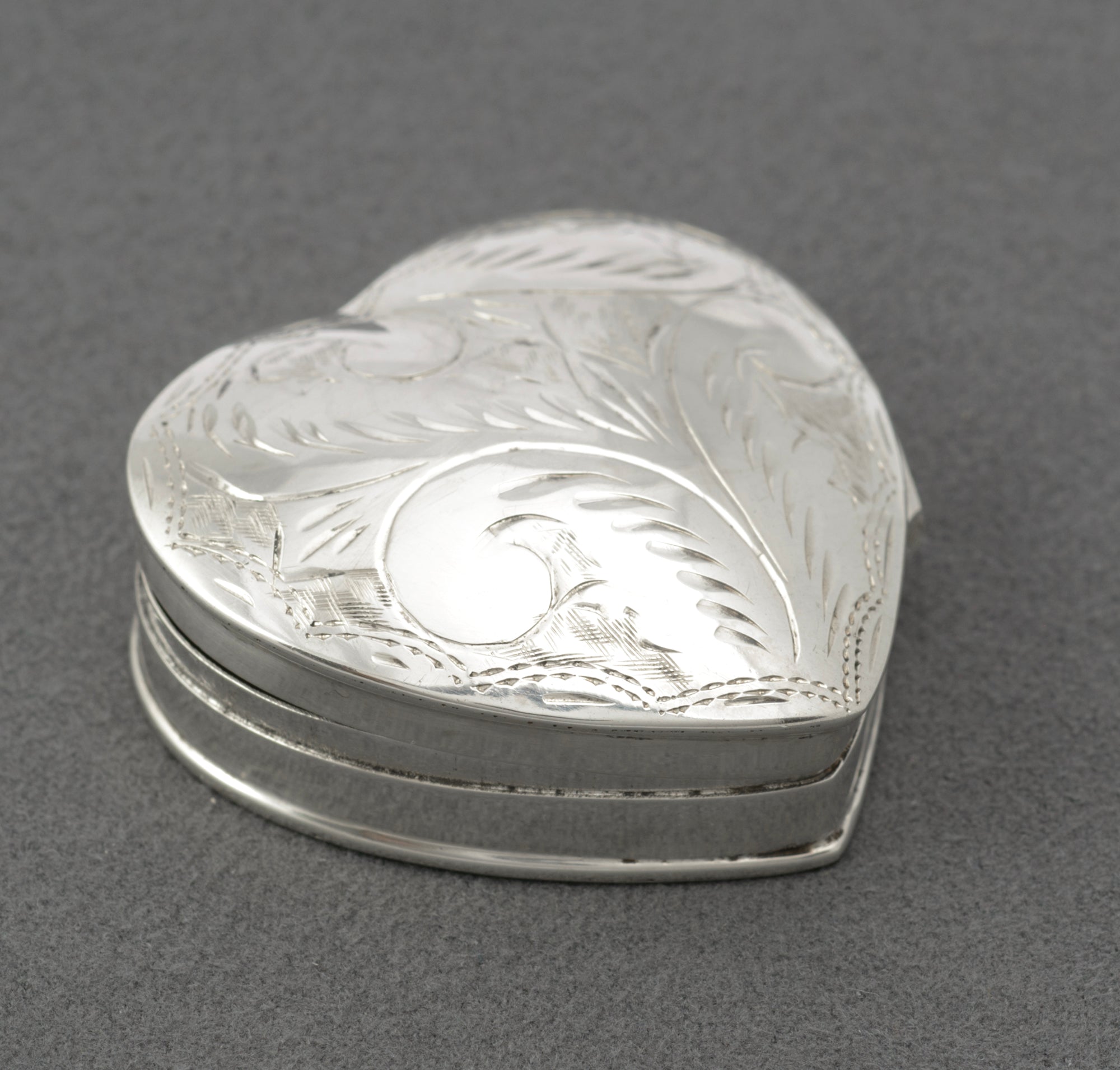 Vintage sterling silver heart shaped trinket box - top view showing full engraved foliate pattern across domed lid