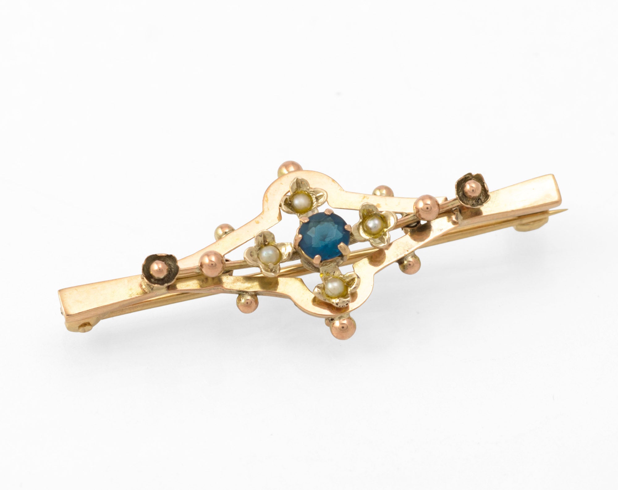 Antique 9ct gold bar brooch - front view showing open geometric frame with central blue glass stone in claw setting, four split seed pearls in flower settings and applied gold bead detail