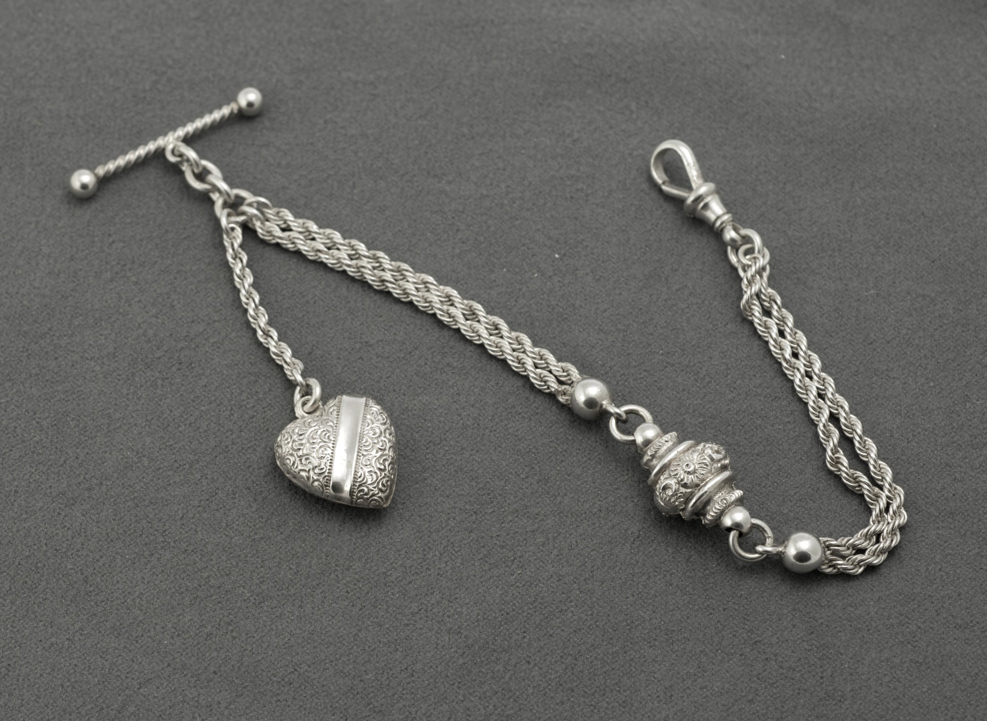 Antique Victorian sterling silver Albertina watch chain - close up of ornate drum-shaped central feature with floral and scrolling detail and polished ball spacers on multi-strand rope chains