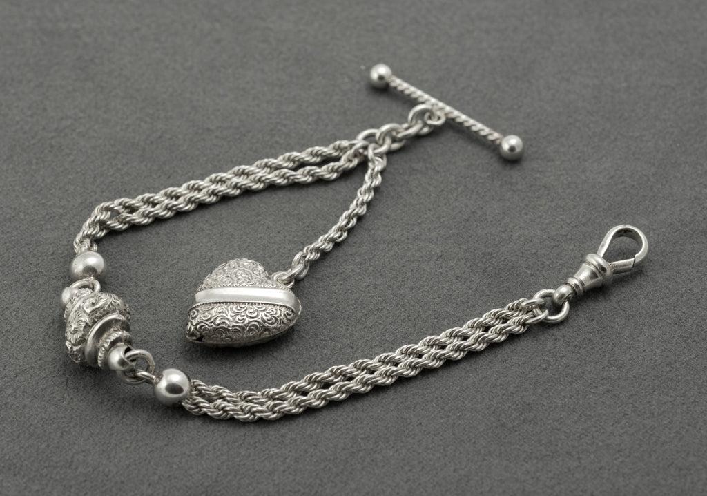 Antique Victorian sterling silver Albertina chain - close up of heart fob front showing dense scrolling decoration and plain central band on softly rounded form