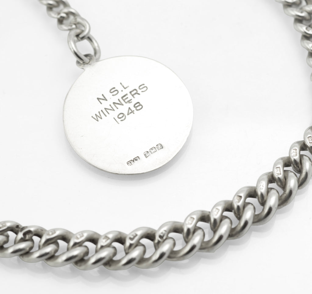 Antique Victorian sterling silver Albert chain - full view on grey background showing graduated curb links, T-bar and fob face with polished shield cartouche and engraved scrolling border