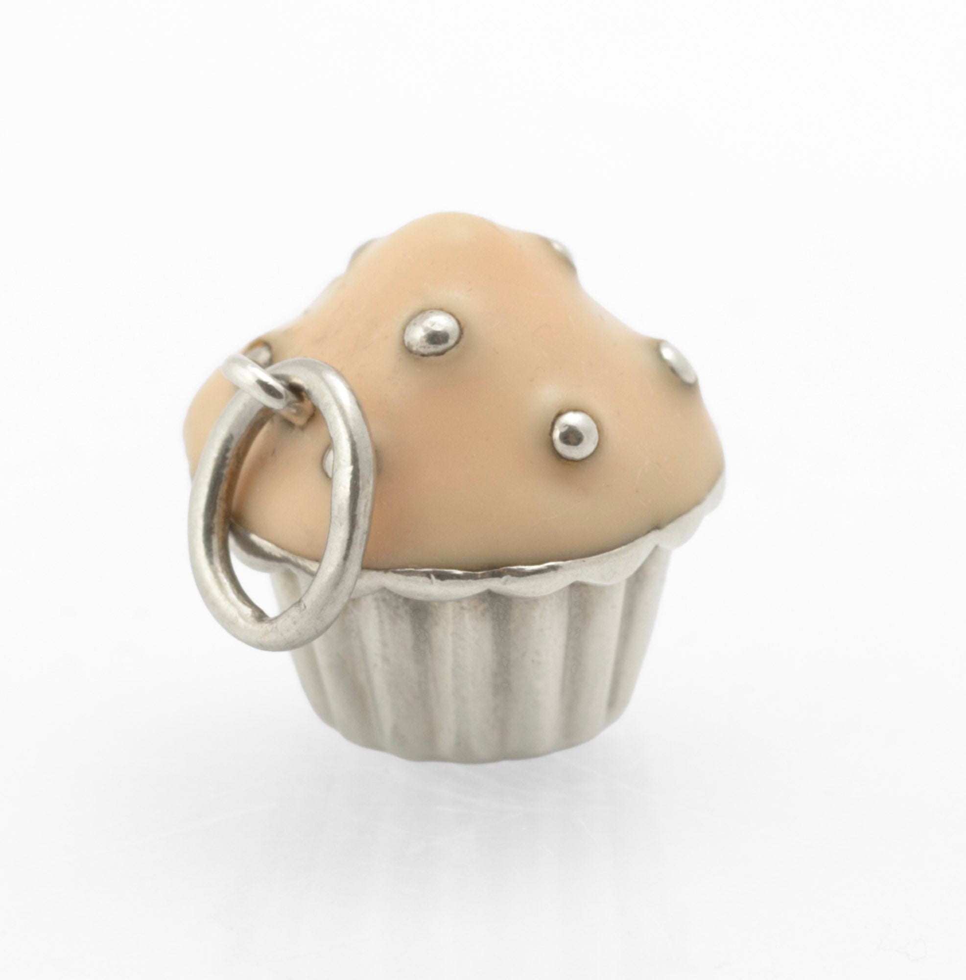 Vintage Tiffany & Co. sterling silver cupcake charm - three quarter view showing fluted silver case, peach enamel top and raised polished silver bead sprinkles with jump ring