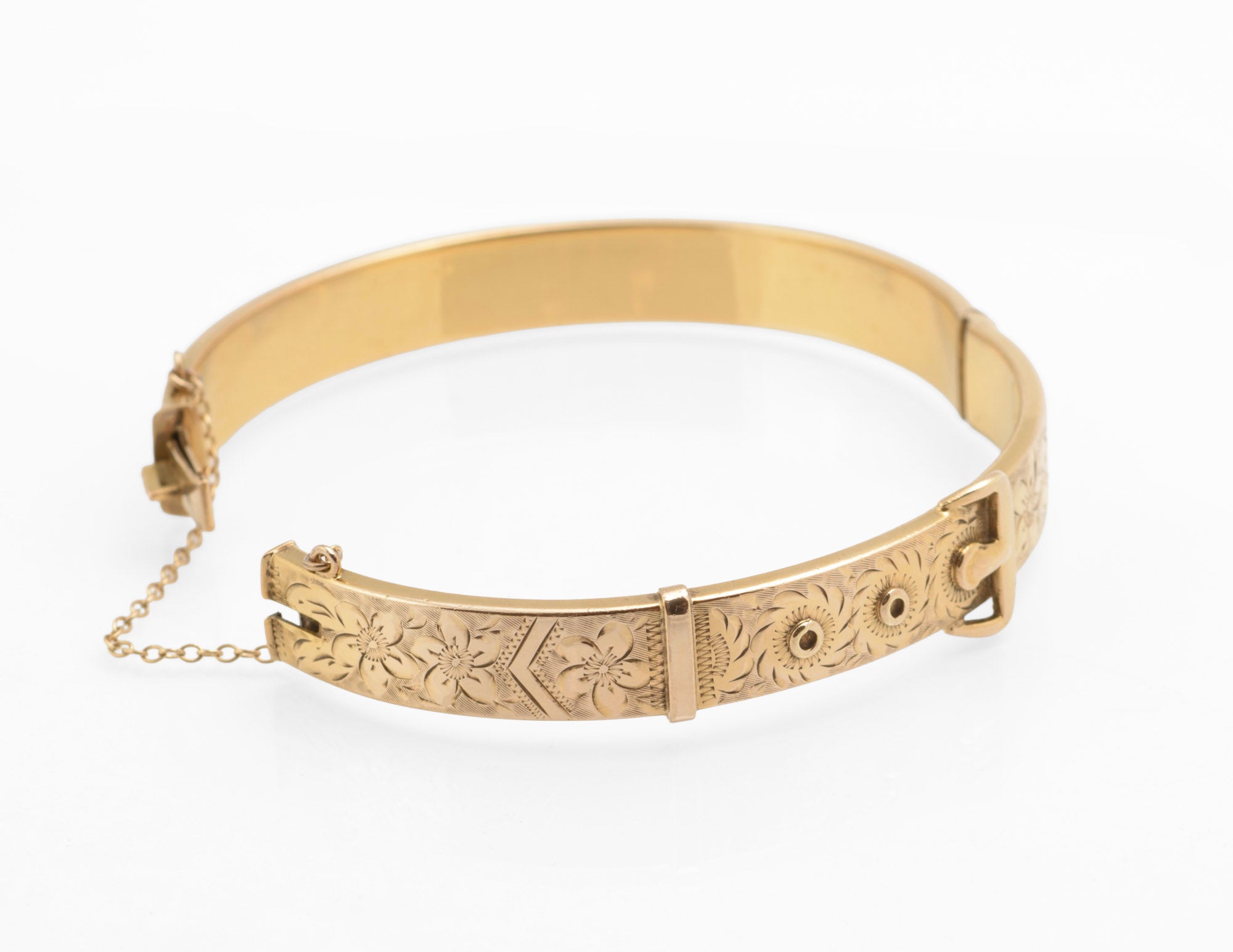 Edwardian gold metal cored buckle bangle - close up of engraved flowers and foliage against textured ground with buckle keeper detail