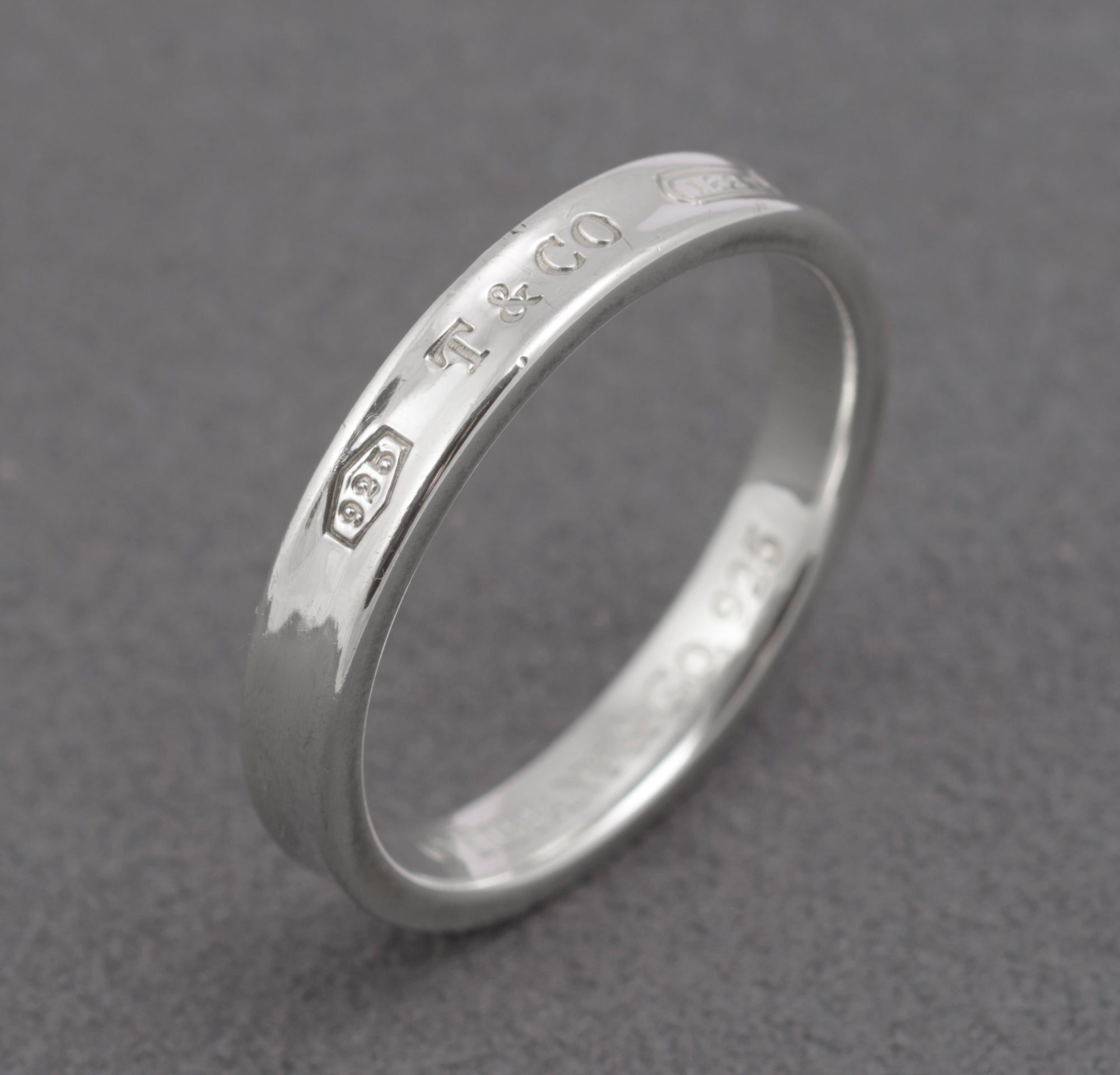 Vintage Tiffany & Co. 1837 sterling silver band ring - angled view on grey background showing engraved 925 T&CO 1837 outer face