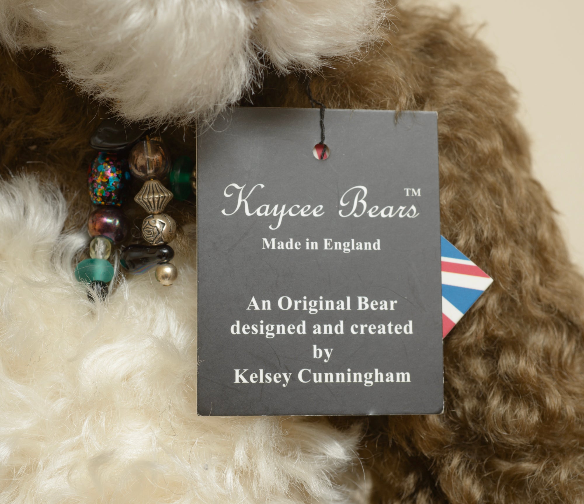 Kaycee Bears Simkin - Kelsey Cunningham - rear view showing dark chocolate curly plush coat, cream ivory tummy panel and AN ORIGINAL Kaycee woven label in gold on dark brown