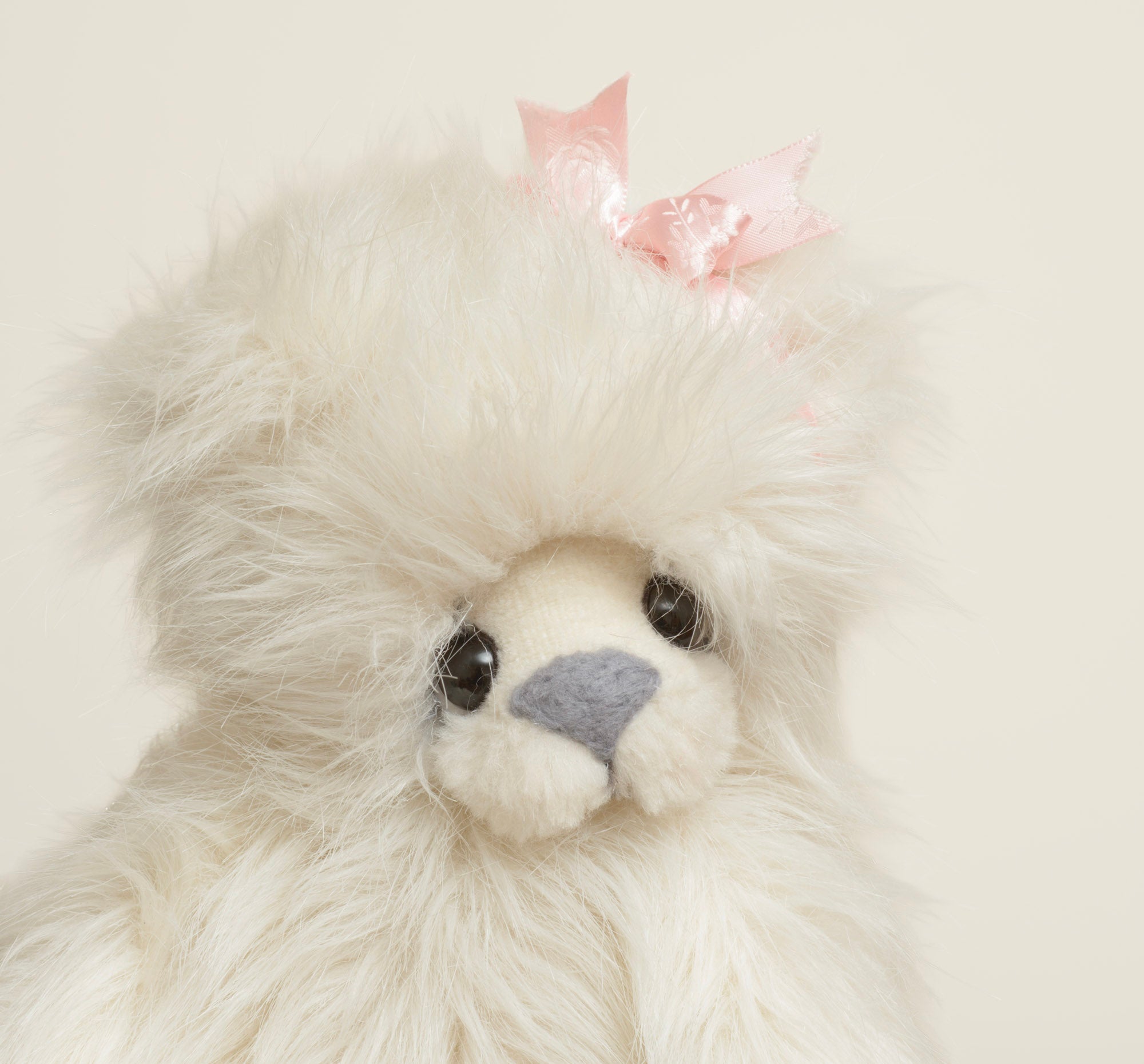 Kaycee Bears Mrs Kaycee - Kelsey Cunningham - close up face showing long cream ivory plush, dark glass eyes with wire lash detail, grey suede effect nose and pink frayed bow