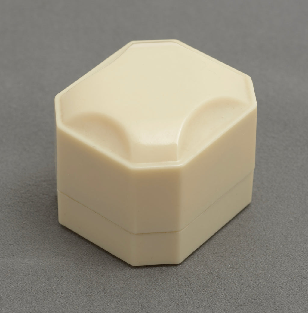 Art Deco ALCA Bakelite ring box - cream - three-quarter rear view showing metal hinge and faceted octagonal body on grey background