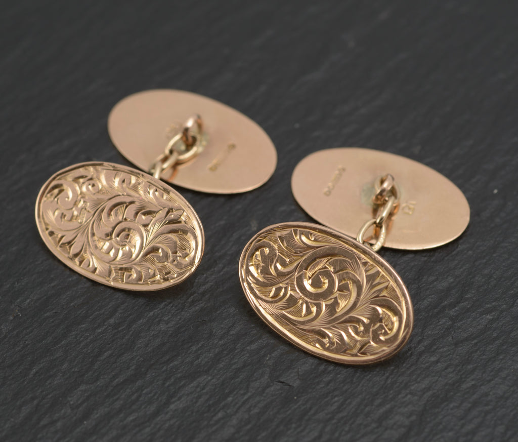 Antique 9ct light rose gold cufflinks - engraved foliate scrolls - three-quarter view showing both cufflinks with engraved front panels and plain reverse panels connected by chain links on dark slate background