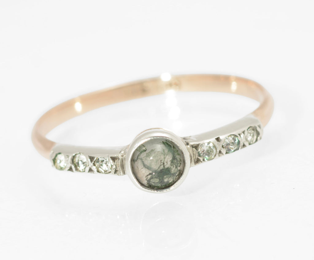 Art Deco moss agate ring - 9ct rose gold and silver - full front view on ring stand showing round natural moss agate cabochon with green branching inclusions in silver bezel with paste set tapered shoulders