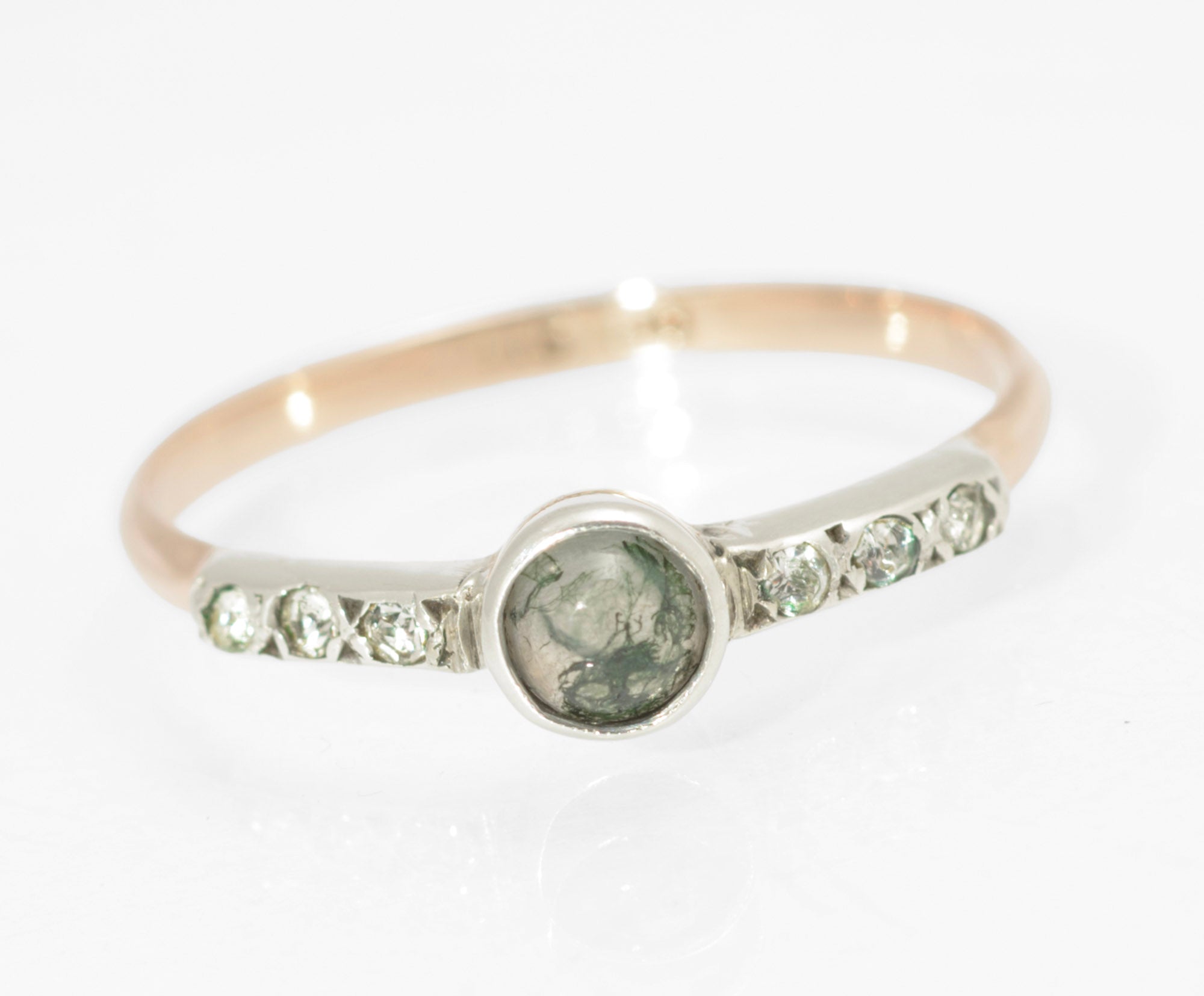 Art Deco moss agate ring - 9ct rose gold and silver - full front view on ring stand showing round natural moss agate cabochon with green branching inclusions in silver bezel with paste set tapered shoulders
