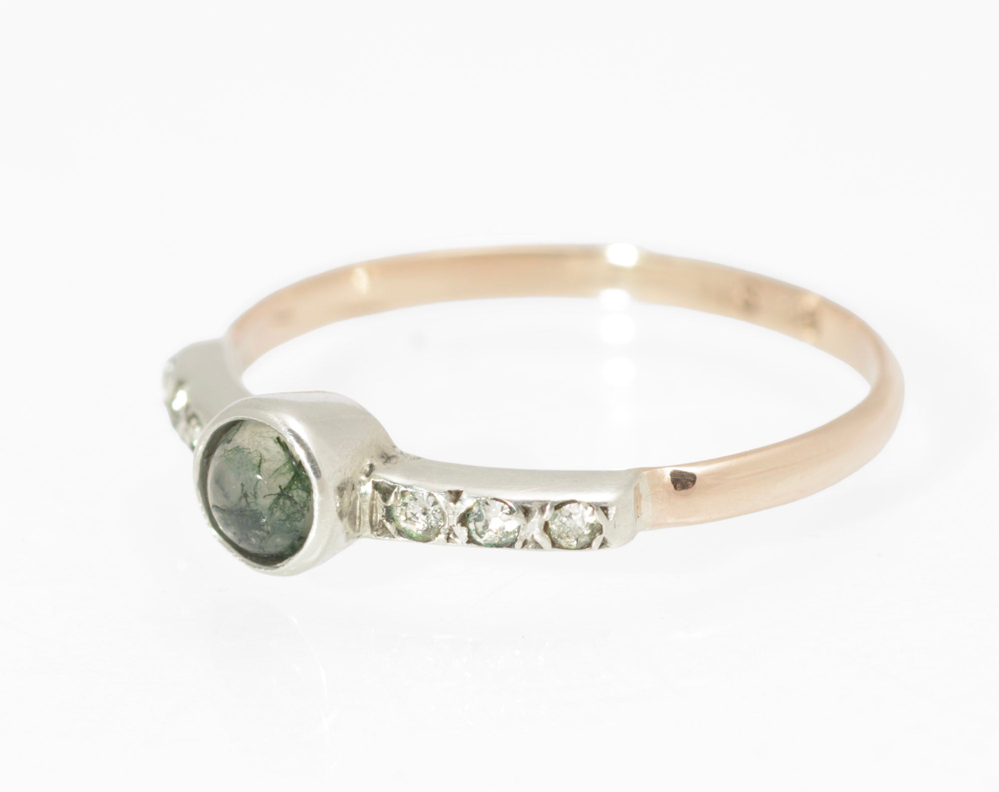Art Deco moss agate ring - 9ct rose gold and silver - angled front view on ring stand showing translucent moss agate cabochon with fine green inclusions and three paste stones to each shoulder