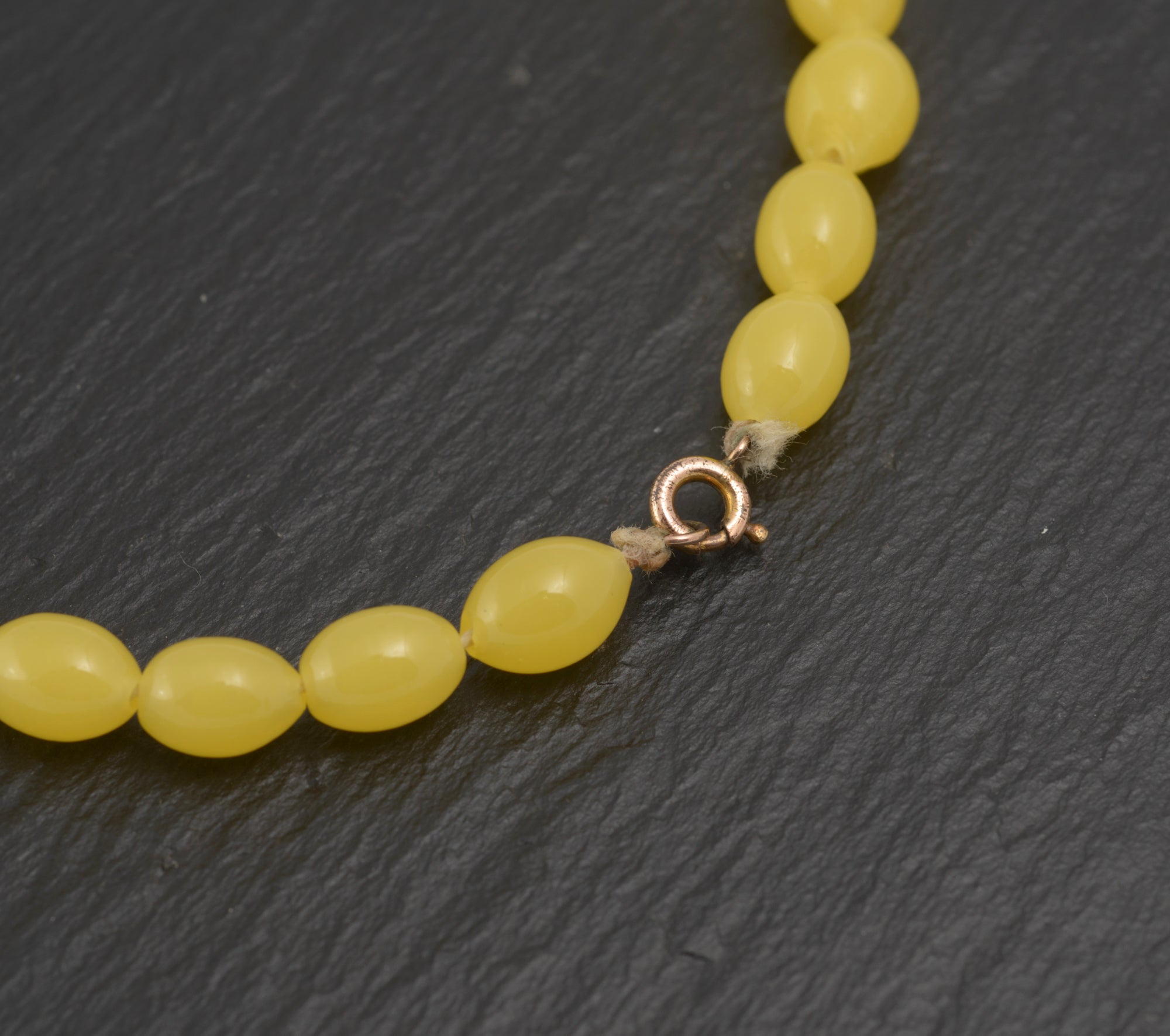 Art Deco uranium vaseline glass bead necklace - vivid opaque yellow - clasp detail showing gold tone spring ring clasp with knotted thread and small graduating beads at clasp end