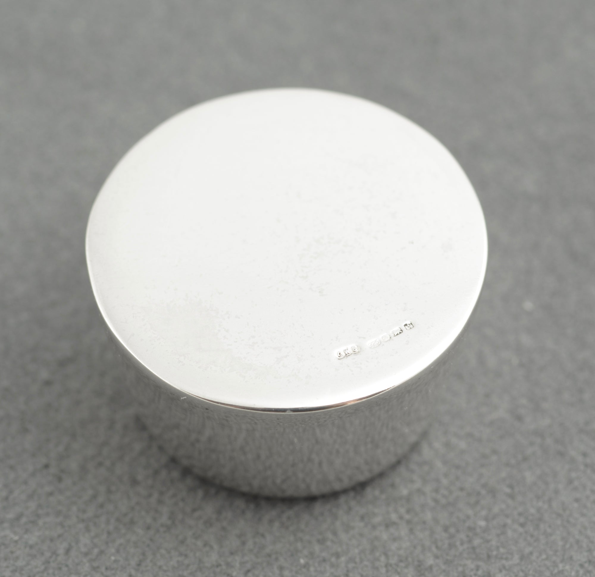 Sterling silver My Last Rolo keepsake - Sheffield 2005 - C. W. Sellors - angled view showing tapered cylindrical form with recessed circular base and high polish finish on grey background