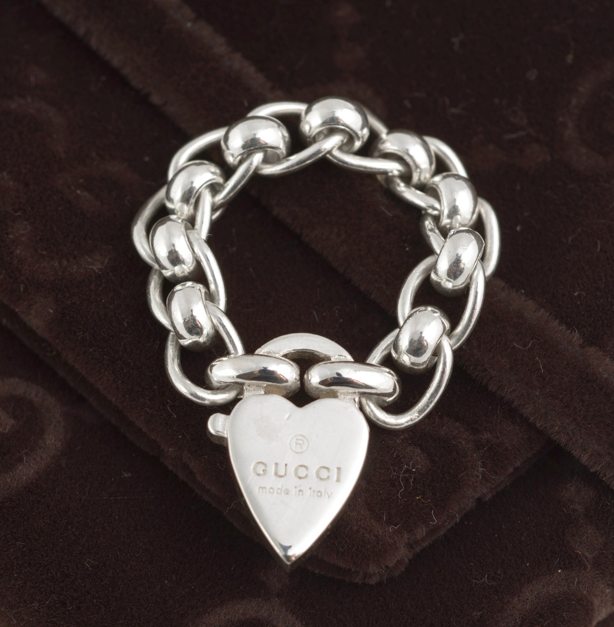 Gucci sterling silver chain link ring with heart charm - front view of heart charm showing Gucci name and made in italy engraving with articulated oval rolo chain links visible on dark background