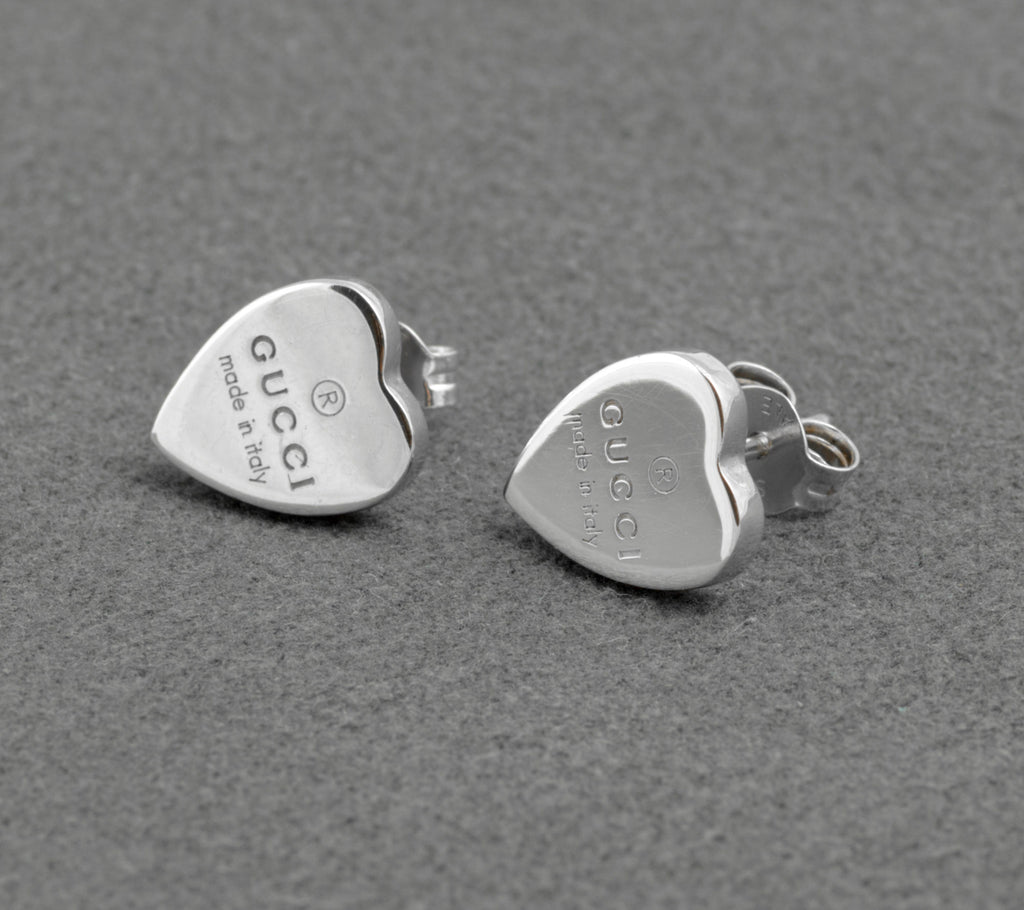 Gucci sterling silver heart stud earrings - made in Italy - pair shown from front and side on grey background showing polished heart form with Gucci name and made in italy engraving and butterfly back fittings
