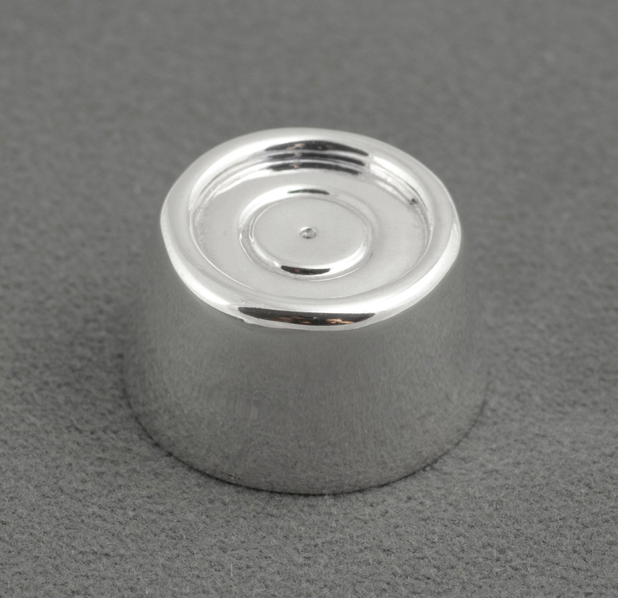 Sterling silver My Last Rolo keepsake - Sheffield 2003 - C. W. Sellors - top view on grey background showing tapered cylindrical form with recessed circular top and concentric ring detail at centre