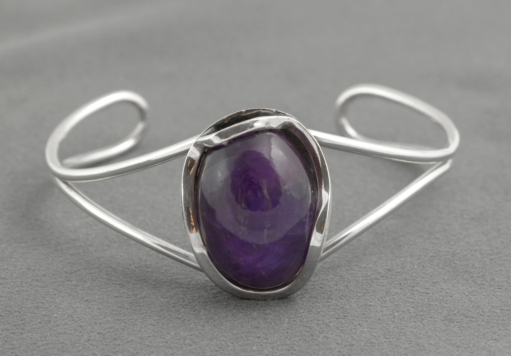 Vintage sterling silver amethyst cabochon bangle - Polish handmade - Gdańsk 925 - three-quarter view on white background showing parallel wire arms curling to scrolled terminals and large amethyst cabochon in open bezel setting