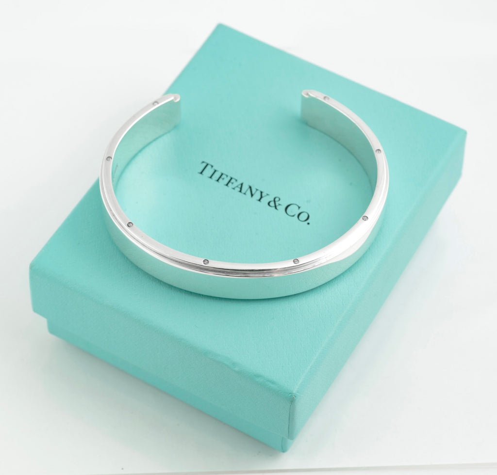 Tiffany and Co Metropolis sterling silver cuff bangle - 925 - top view on grey background showing full circumference of flat top face with flush set screw head details along both edges and high mirror polish finish