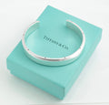 Tiffany and Co Metropolis sterling silver cuff bangle - 925 - top view on grey background showing full circumference of flat top face with flush set screw head details along both edges and high mirror polish finish