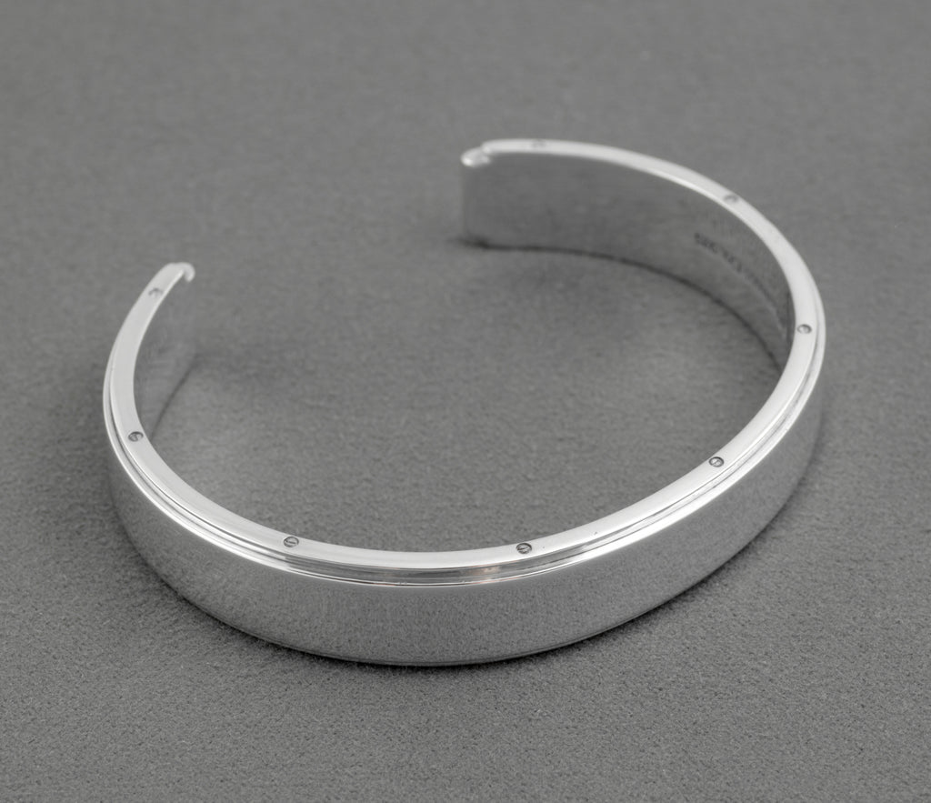 Tiffany and Co Metropolis sterling silver cuff bangle - 925 - three-quarter front view on grey background showing flat top face screw head edge detail and open cuff ends with rounded inner profile