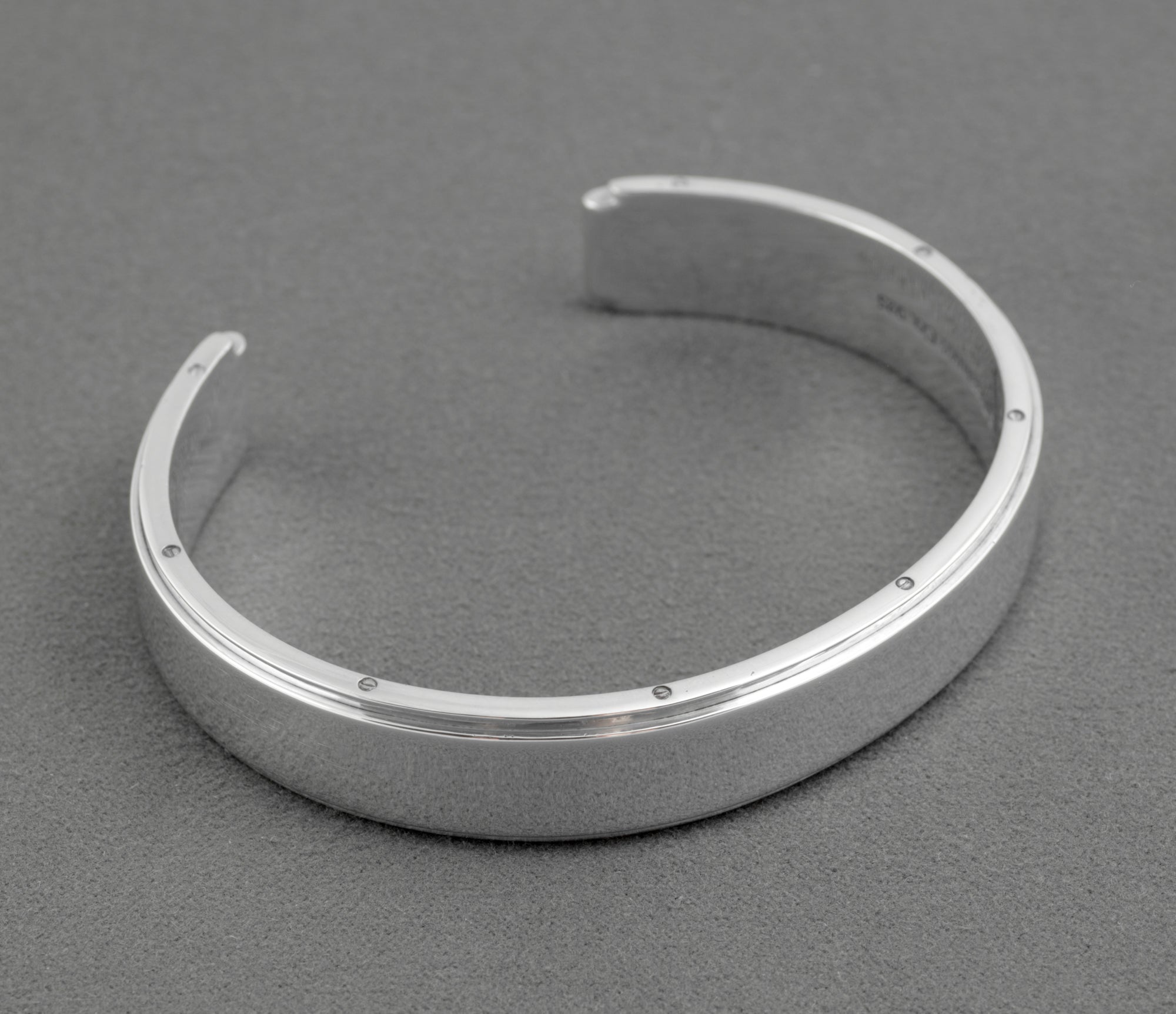Tiffany and Co Metropolis sterling silver cuff bangle - 925 - three-quarter front view on grey background showing flat top face screw head edge detail and open cuff ends with rounded inner profile