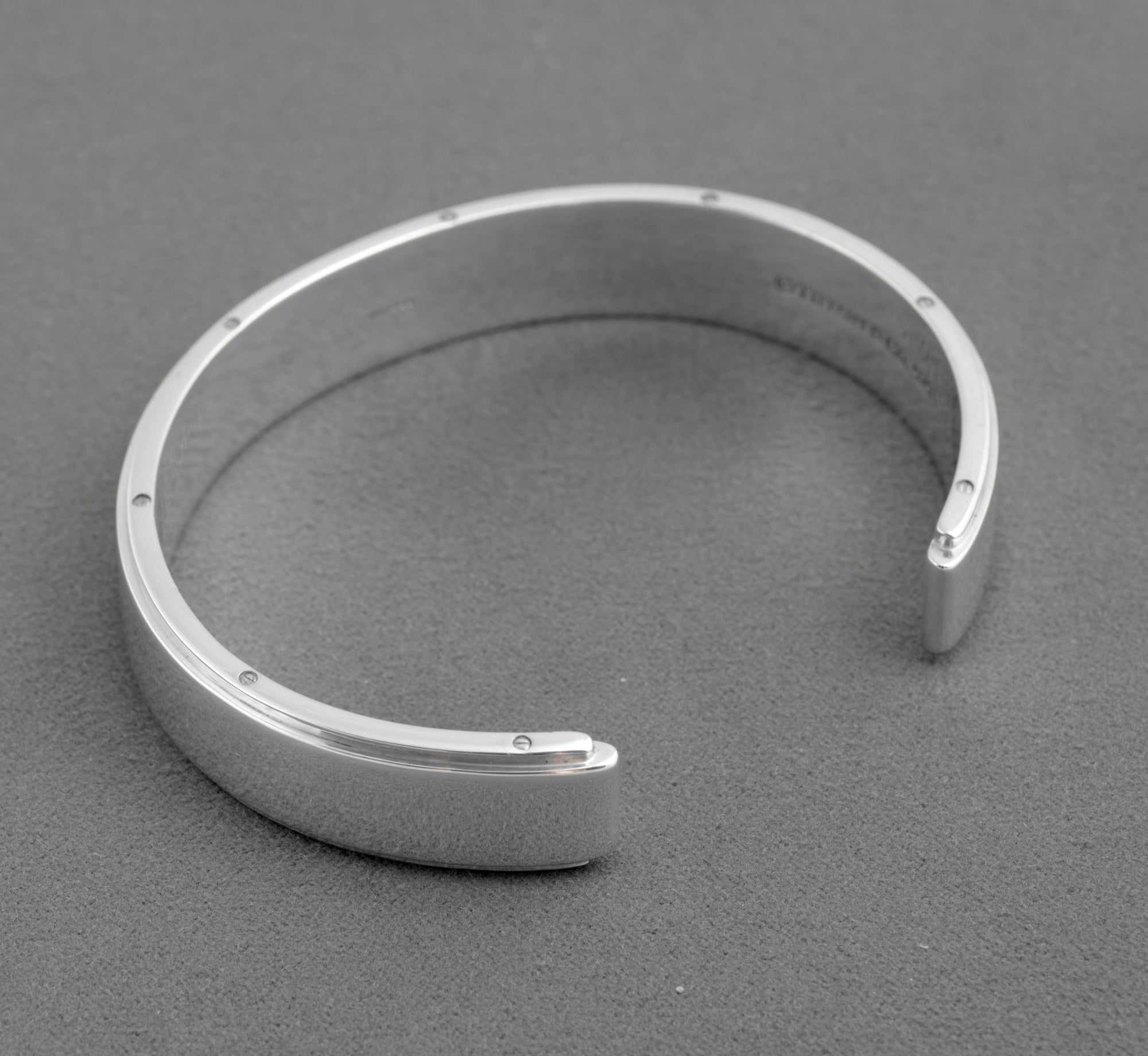 Tiffany and Co Metropolis sterling silver cuff bangle - 925 - underside view on grey background showing full circumference of screw head edge detail and inner rounded profile of cuff