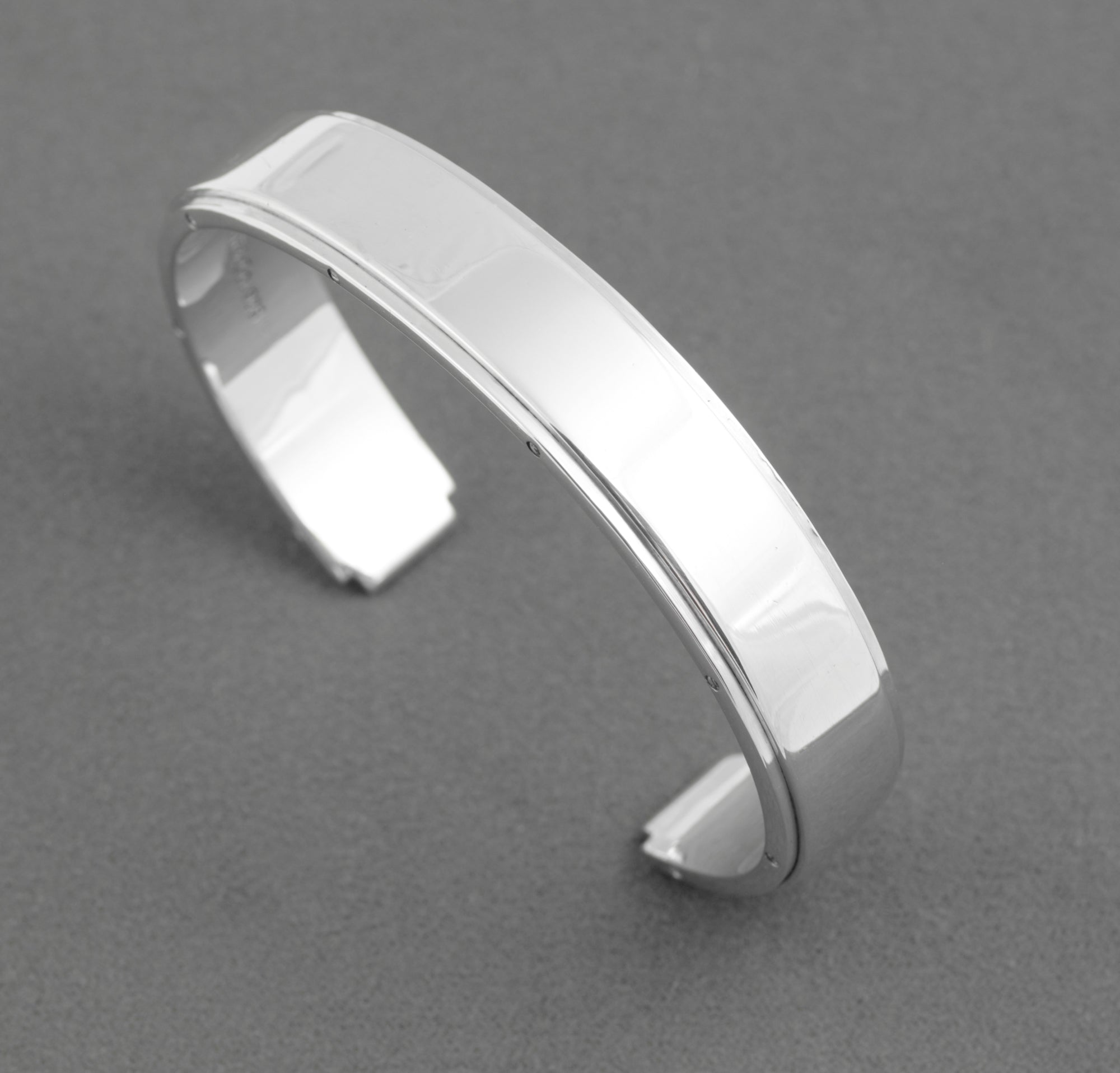 Tiffany and Co Metropolis sterling silver cuff bangle - 925 - angled top view on grey background showing mirror polished flat top face with screw head edge detail and open cuff ends