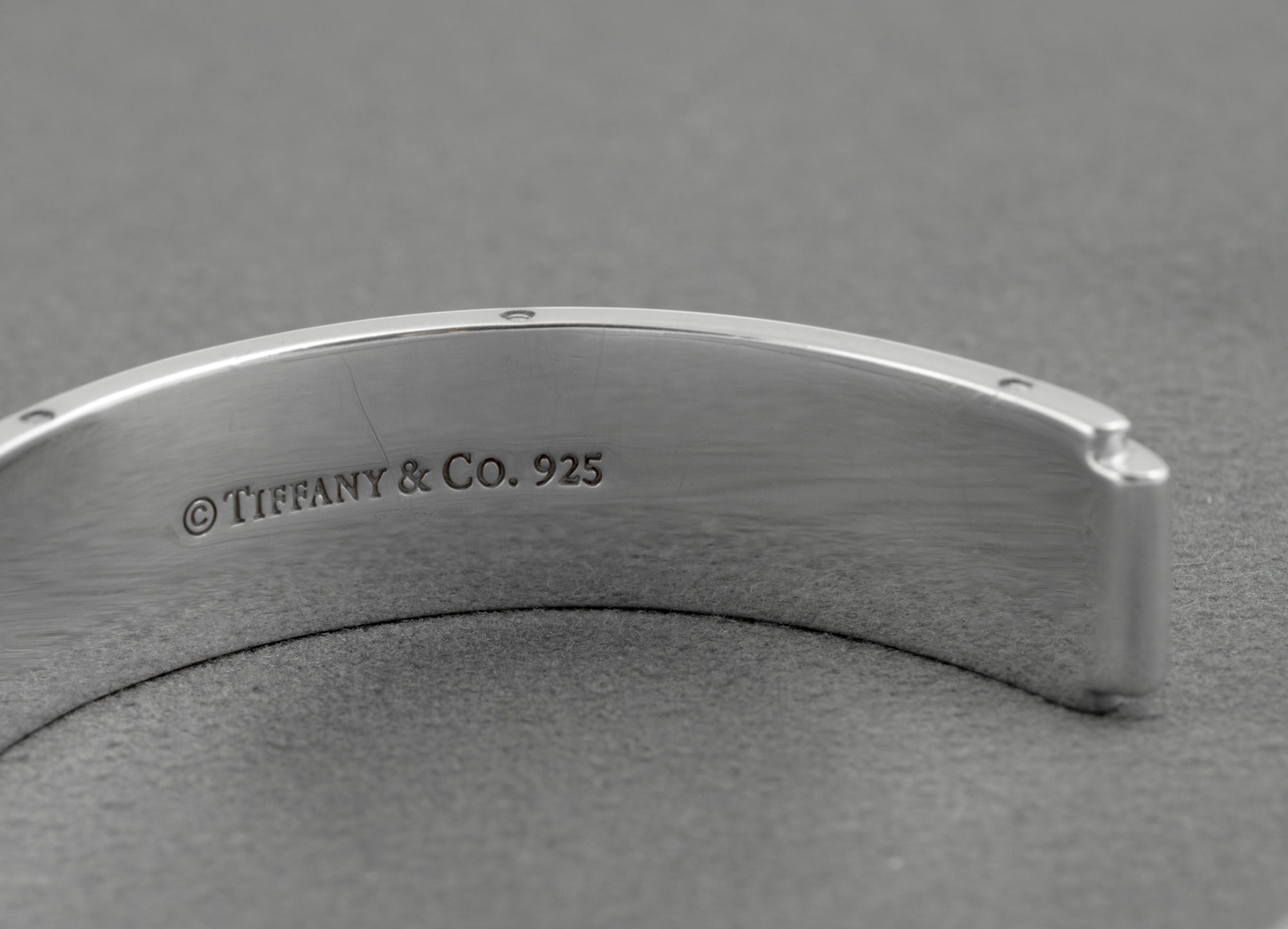 Tiffany and Co Metropolis sterling silver cuff bangle - 925 - angled rear view on grey background showing inner rounded profile screw head edge detail and open cuff form