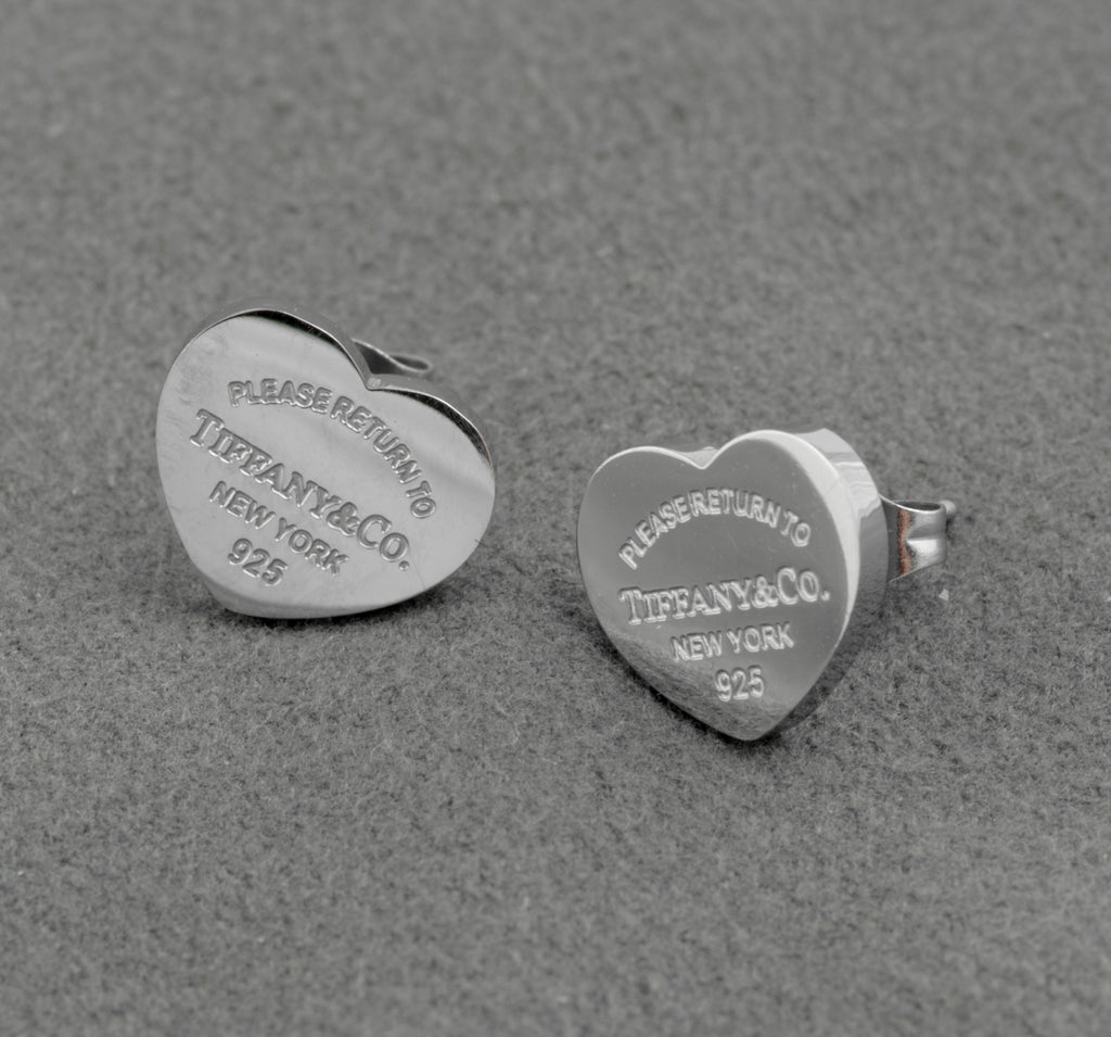 Pair of Tiffany and Co Return to Tiffany sterling silver heart stud earrings on grey background showing engraved inscription to face and butterfly back fittings