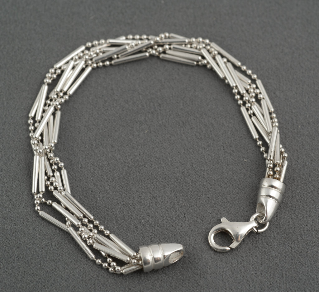 Vintage sterling silver six strand bar and bead bracelet open clasp view showing both tapered torpedo terminals and lobster clasp with connecting ring on dark grey background