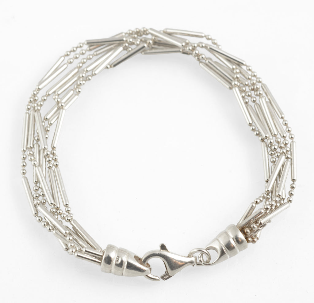 Vintage sterling silver six strand bar and bead bracelet with tapered torpedo terminals and lobster clasp laid in circle on white background showing full length 19cm construction