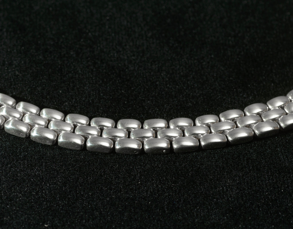 Close up macro shot of heavy sterling silver three row brick link necklace on black background showing individual articulated rectangular links in interlocking brick pattern