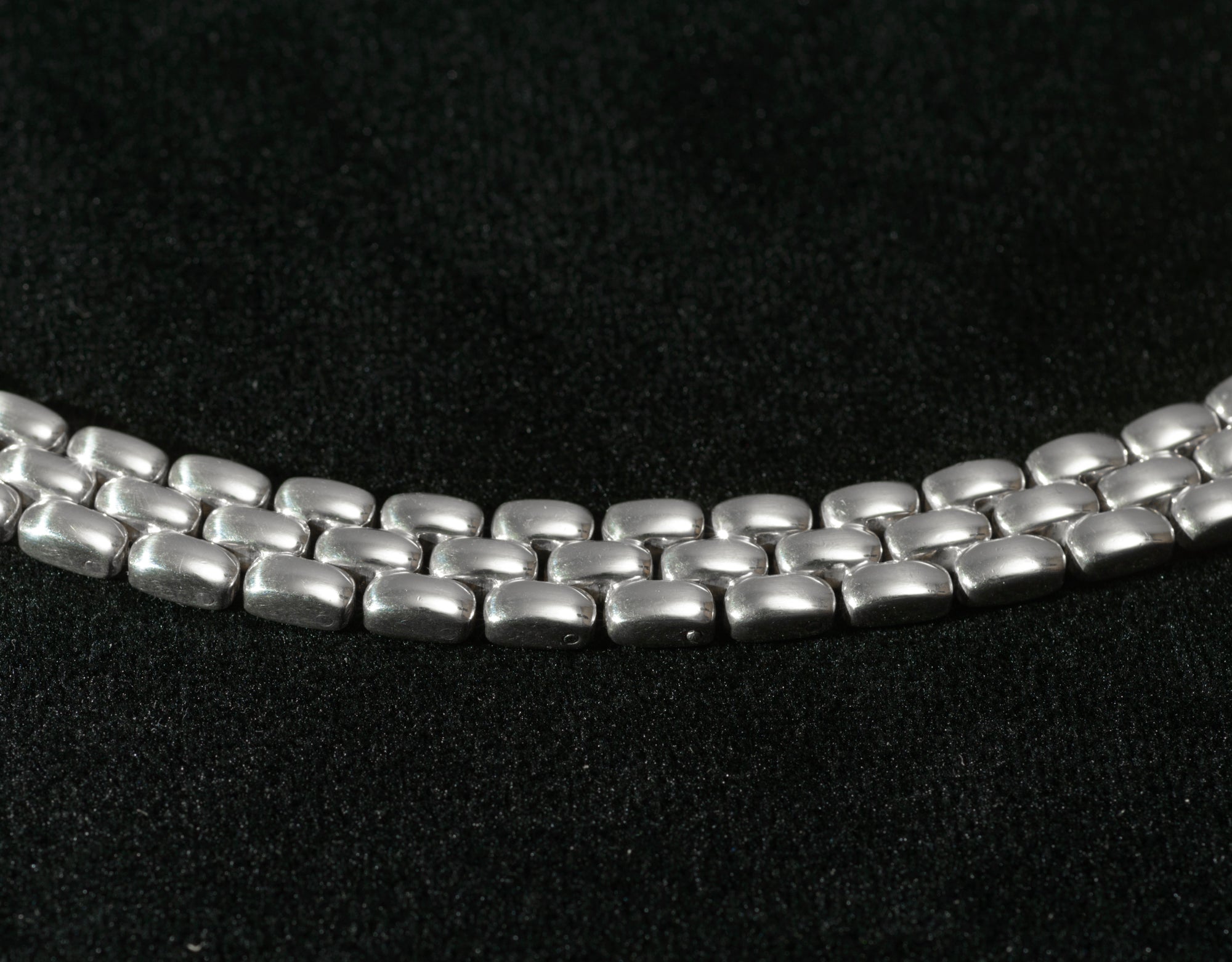 Close up macro shot of heavy sterling silver three row brick link necklace on black background showing individual articulated rectangular links in interlocking brick pattern
