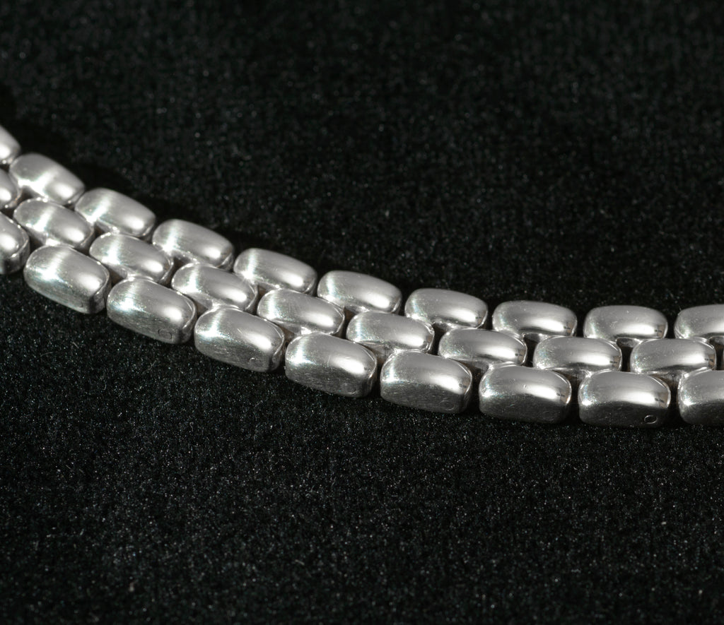 Close up macro shot of heavy sterling silver three row brick link necklace on black background showing reverse side of articulated rectangular links and individual link movement