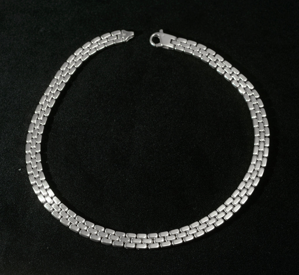 Close up of heavy sterling silver three row brick link necklace end fitting on black background showing reverse of end fitting and connection to brick link chain