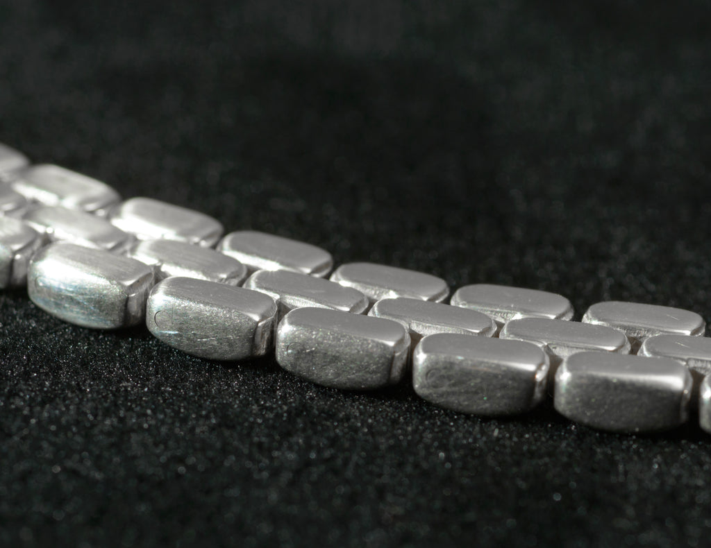 Close up of heavy sterling silver three row brick link necklace flat lobster clasp on black background showing clasp mechanism and integration with full width of necklace