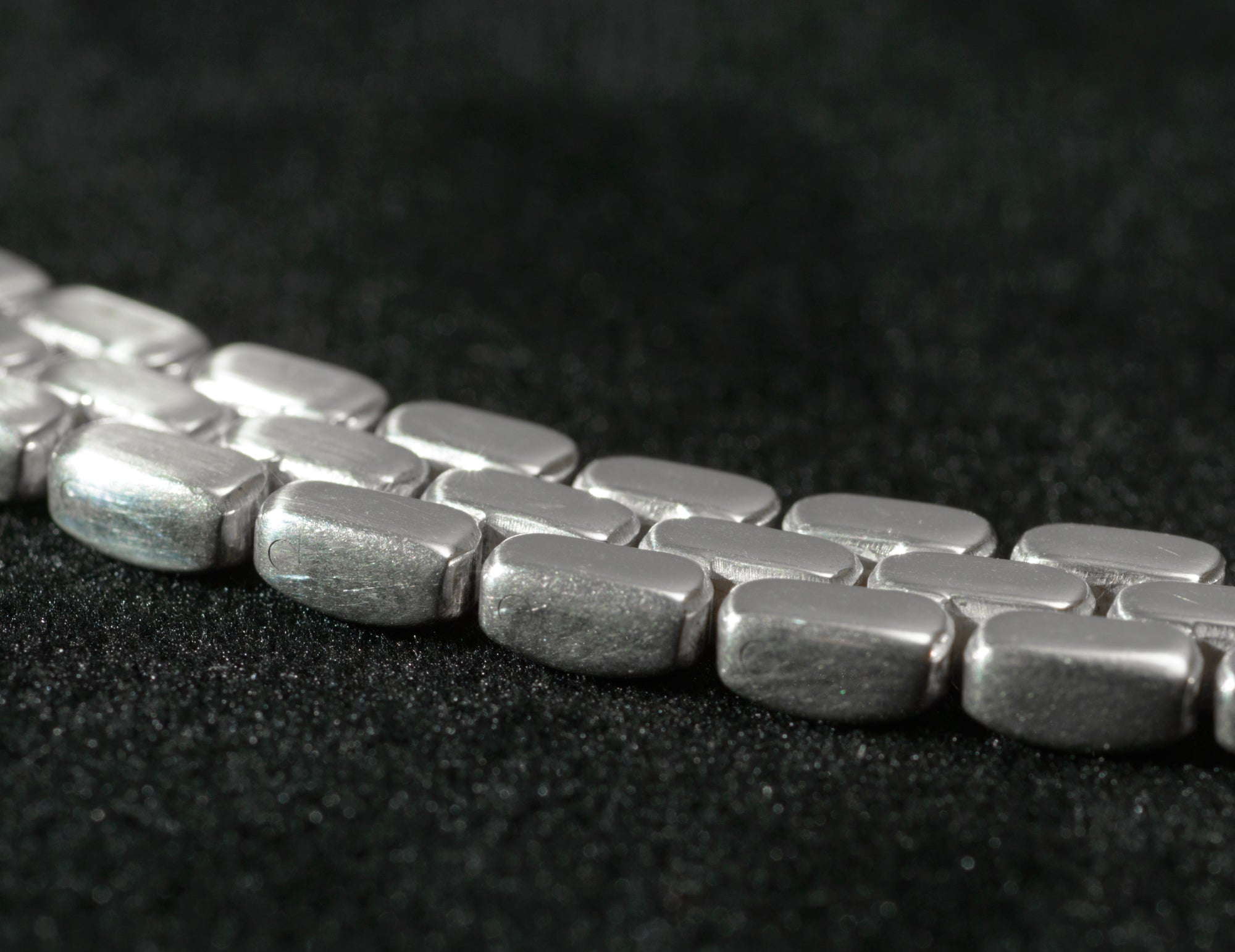 Close up of heavy sterling silver three row brick link necklace flat lobster clasp on black background showing clasp mechanism and integration with full width of necklace