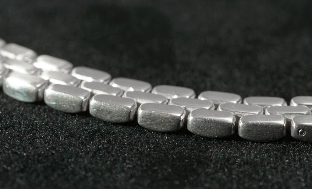 Heavy sterling silver three row brick link necklace laid flat on black background showing mid section of chain and brick link construction from above