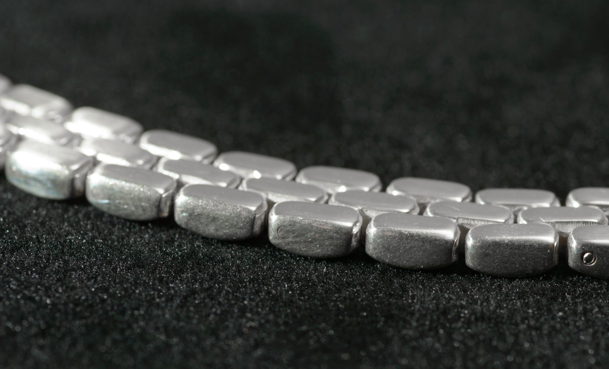 Heavy sterling silver three row brick link necklace laid flat on black background showing mid section of chain and brick link construction from above