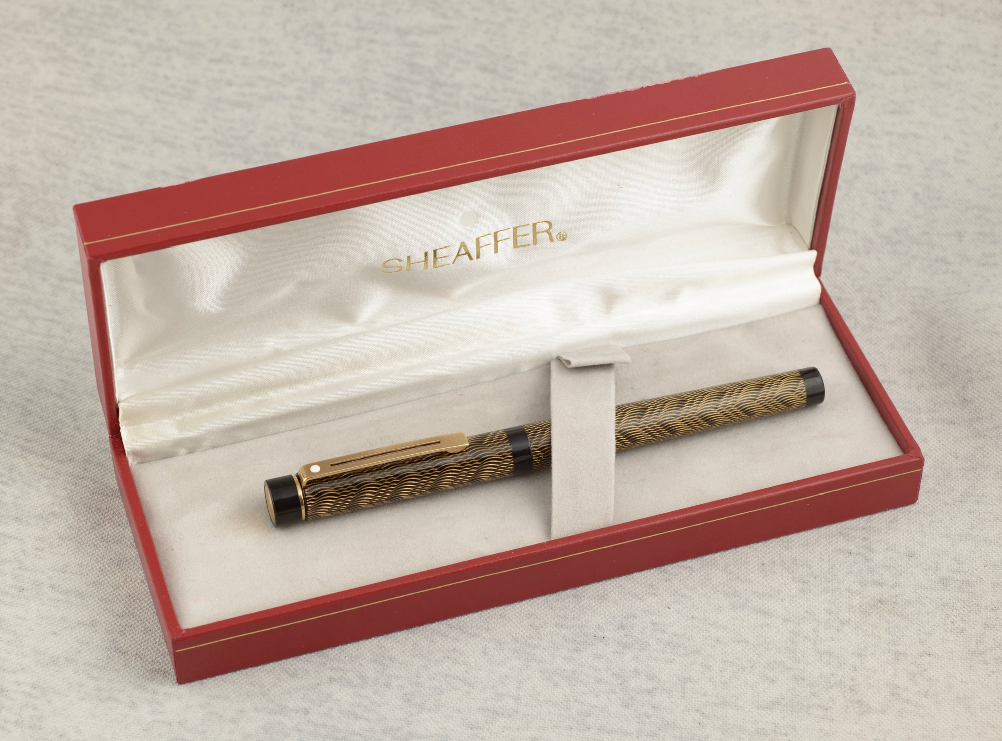 Sheaffer Targa 676 Classic fountain pen Gold Feather finish with original red Sheaffer presentation case open showing cream satin interior and soft grey pouch on linen background