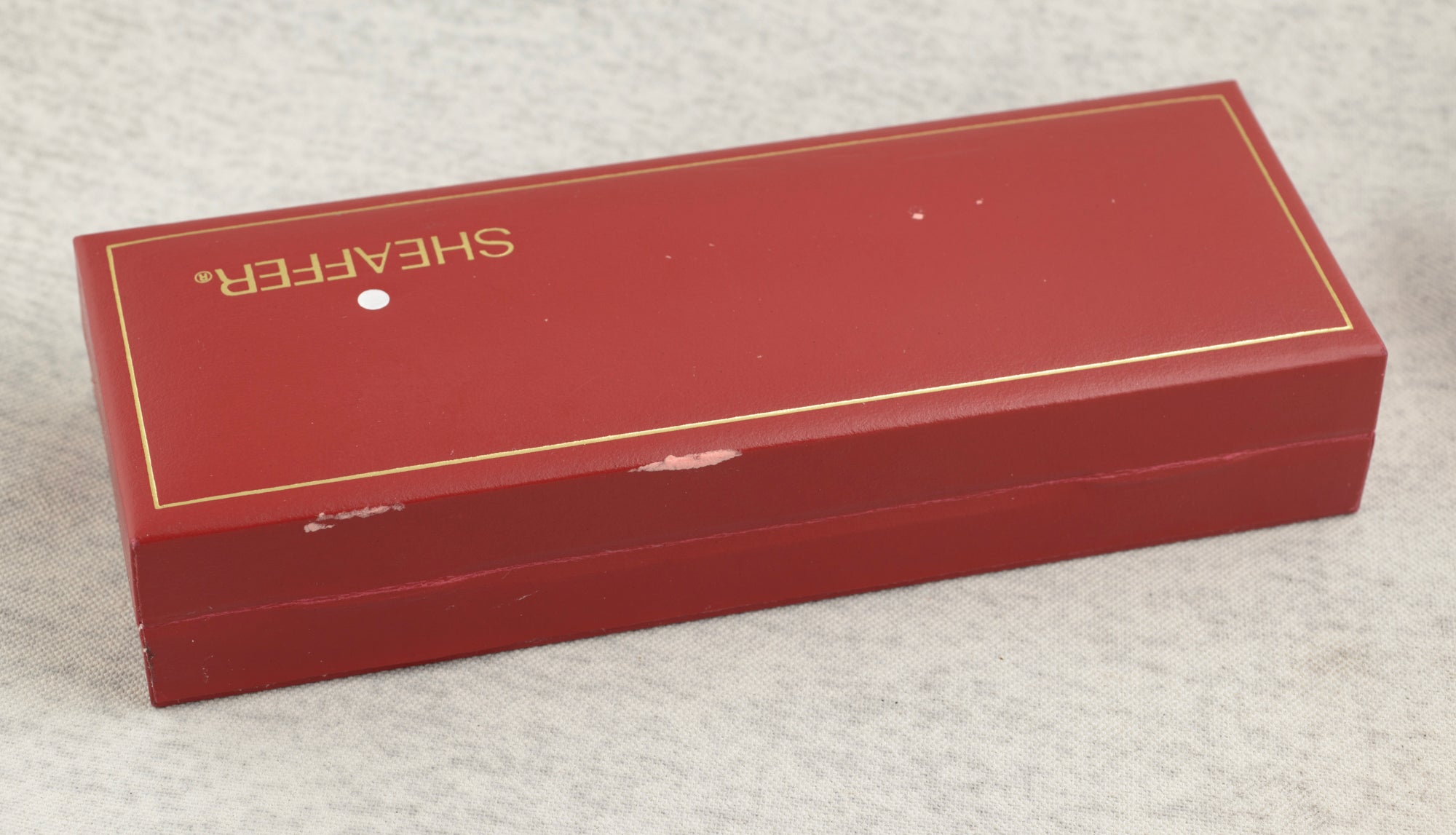 Sheaffer Targa 676 Classic fountain pen Gold Feather finish assembled with cap fitted lying diagonally on linen background showing full length of pen with gold tone clip and white dot