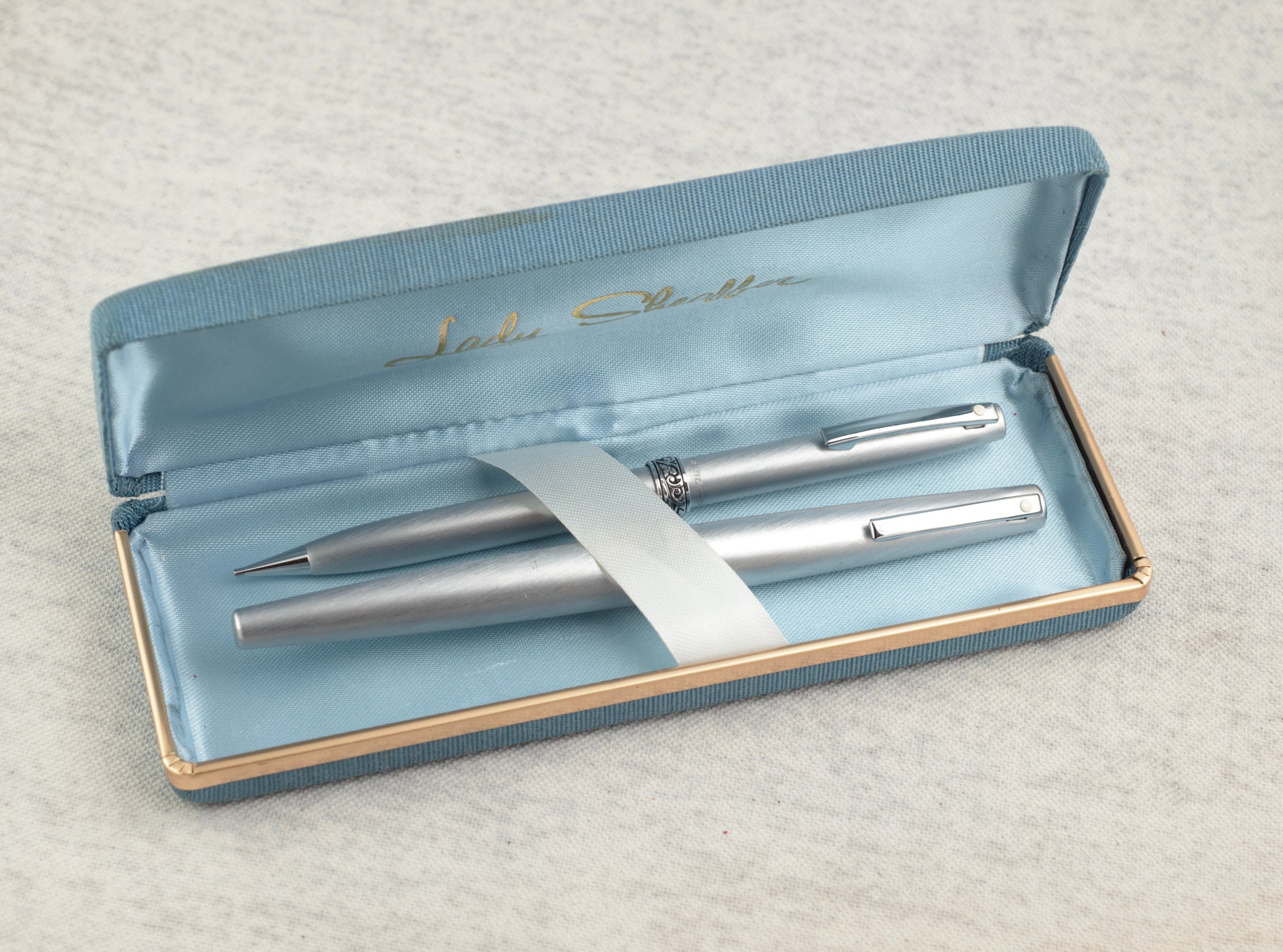 Lady Sheaffer 620 Florentine fountain pen and mechanical pencil set in brushed silver tone finish lying side by side on linen background showing acanthus scrollwork Florentine bands and pocket clips with white dots