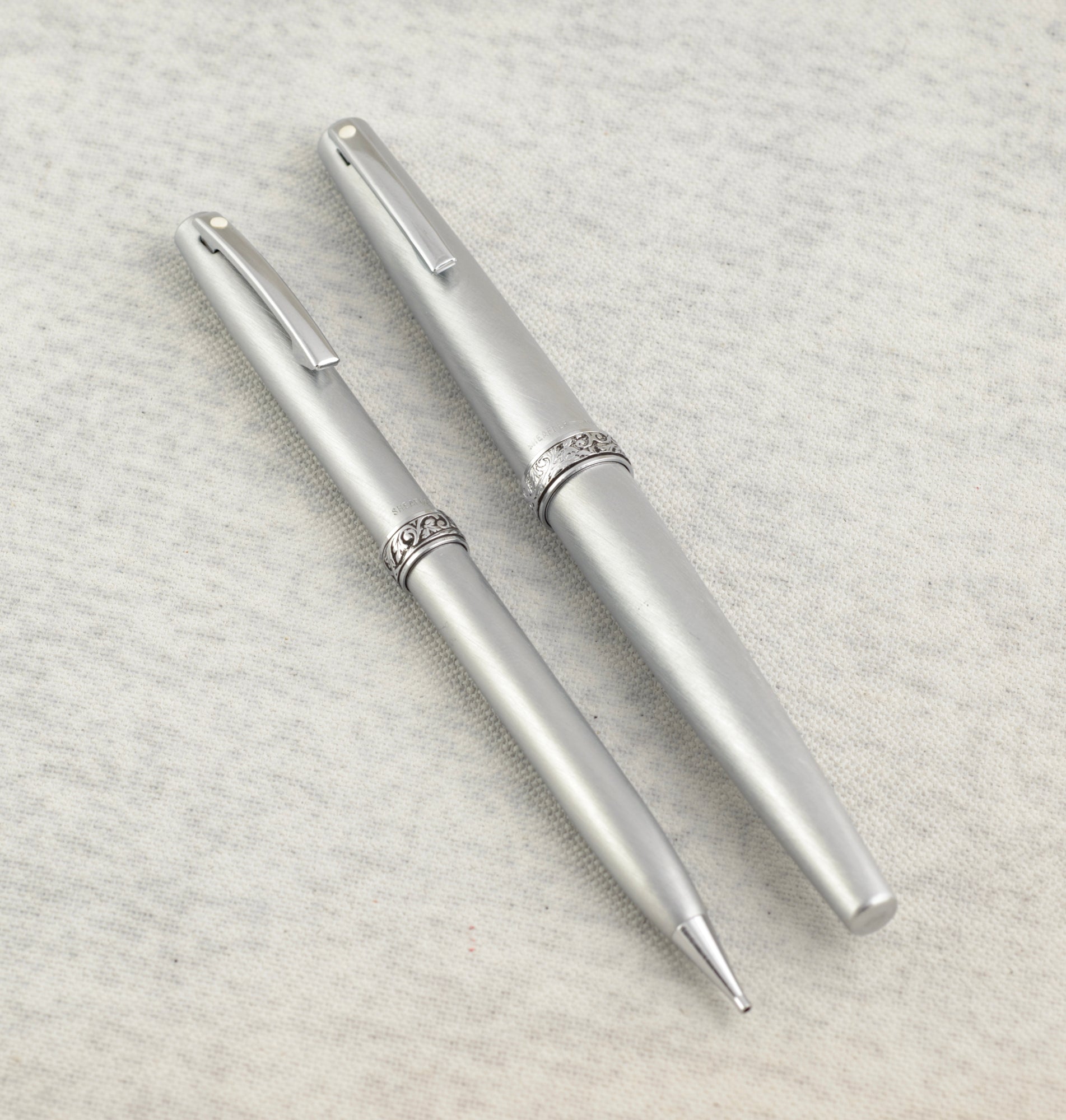 Lady Sheaffer 620 Florentine set disassembled on linen background showing fountain pen cap barrel with converter pencil cap and pencil barrel as four separate components