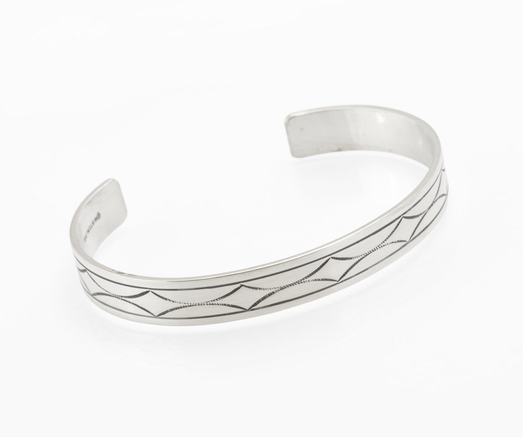 Vintage sterling silver open cuff bangle with hand engraved geometric star and diamond pattern between parallel border lines on white background top view