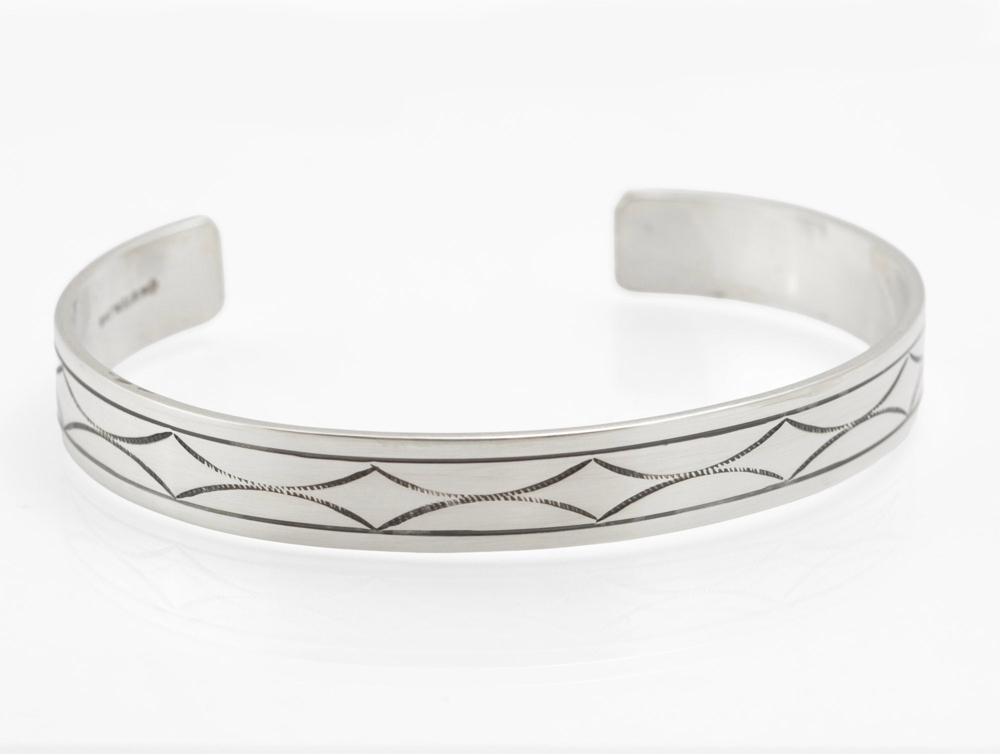 Vintage sterling silver open cuff bangle with hand engraved geometric pattern side view showing cuff opening and band profile on white background